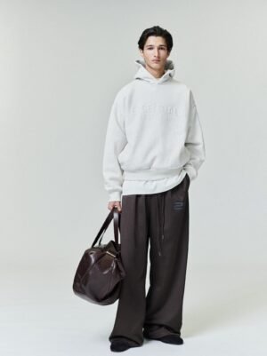 Detailed views and lifestyle shots of the authentic 2026 Essentials oatmeal grey full-zip hoodie, featuring a classic relaxed fit and premium fleece texture, managed by Zizzle LLC.