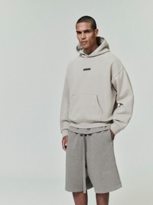 Full lifestyle shots of a model wearing the authentic Oatmeal Essentials hoodie with a beveled metallic logo and matching relaxed shorts, curated by Zizzle LLC.